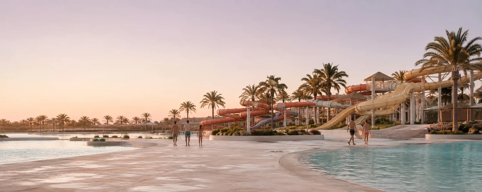 Water slides and pools at a palm-lined water park at golden hour